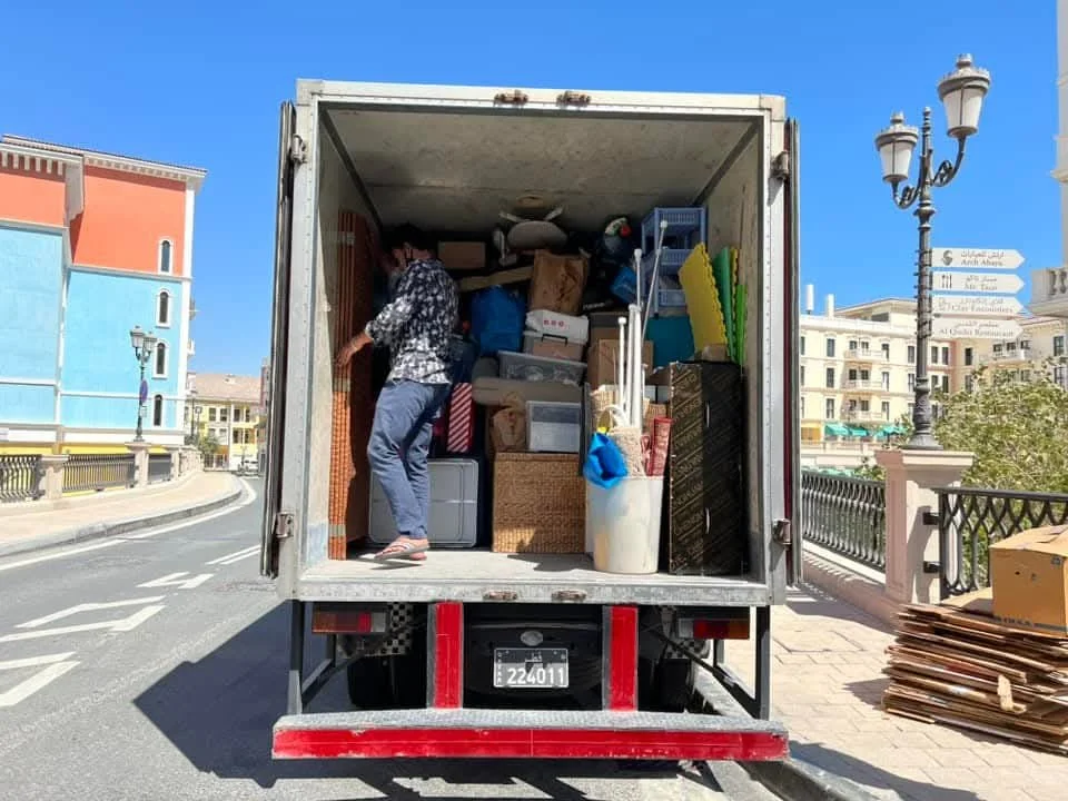 Professional movers protecting furniture during a hot summer move in Doha